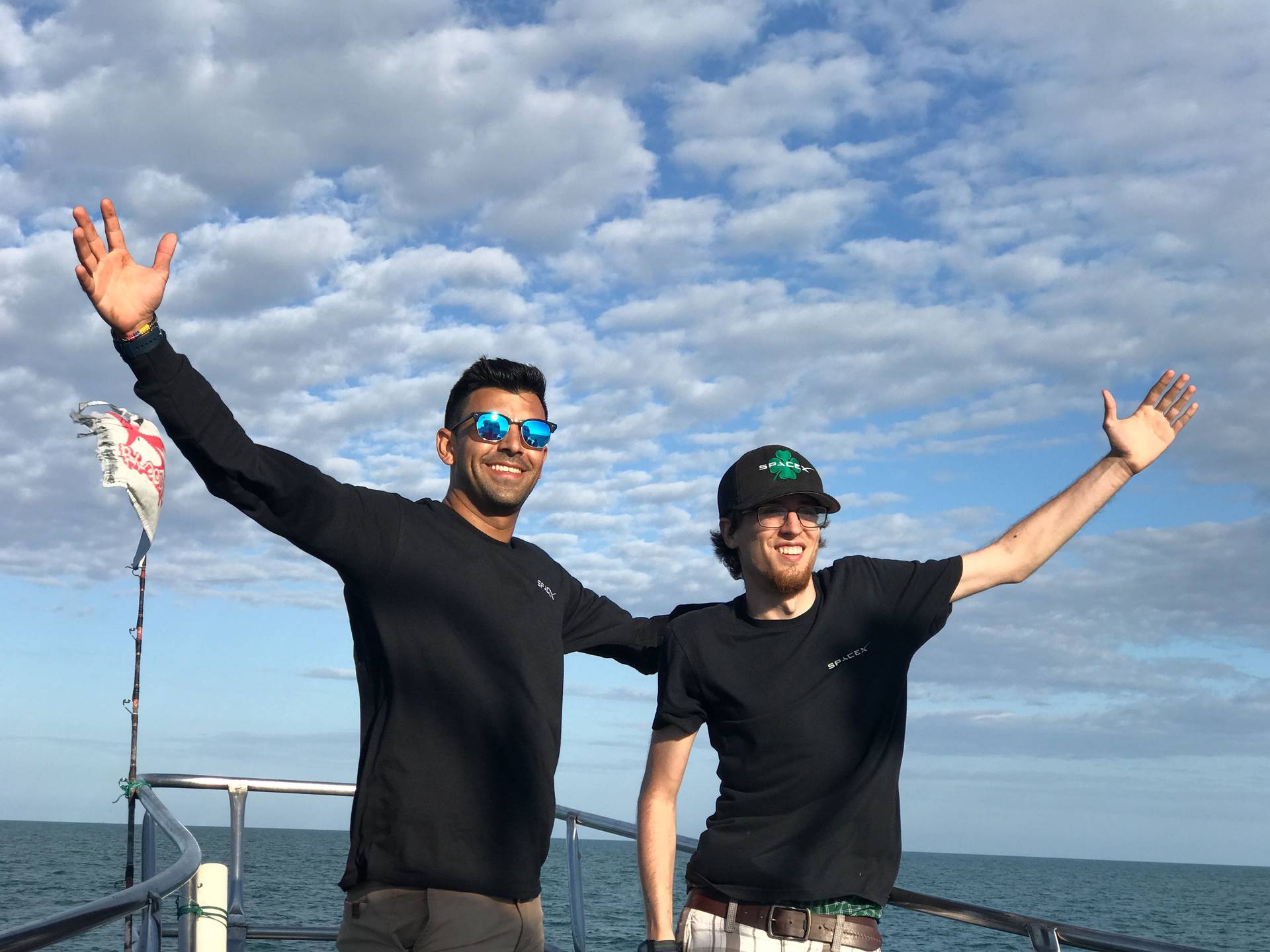 Photograph of CAM and Steven on the boat with their arms spread in a greeting